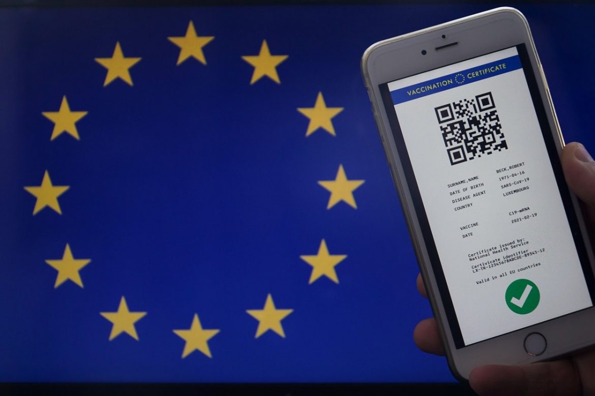 The digital green certificate of the european union with the QR code on the screen of a mobil phone held by a hand in airport for travel. Vaccination